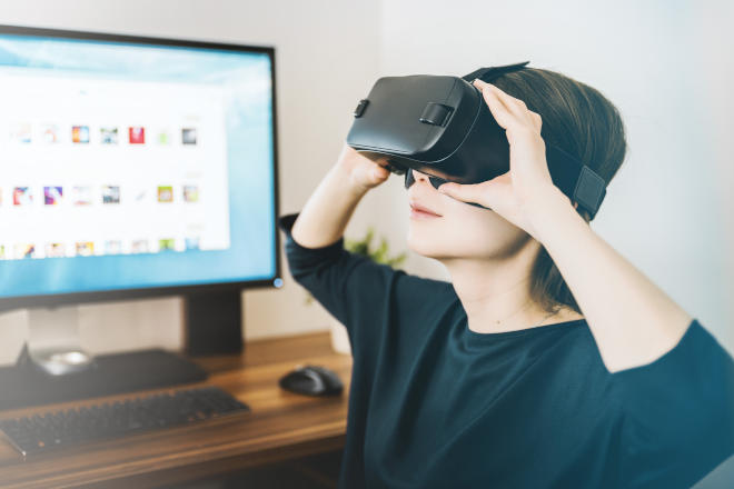 Eine Frau nutzt ein VR-Headside neben einem Computer